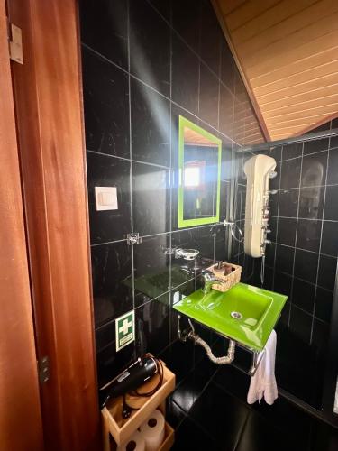 a green sink in a black tiled bathroom at Maurícius Village in Santa Cruz
