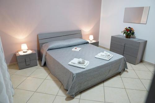 sypialnia z łóżkiem i 2 szafkami nocnymi z ręcznikami w obiekcie Bono Vacanze Casa Bono w mieście Sciacca