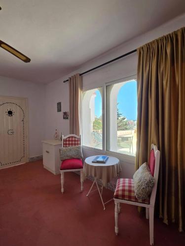 a room with a table and chairs and a large window at Nanou in Zarzis