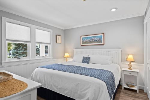 a white bedroom with a bed and two windows at 111 Water Street Inn in Boyne City