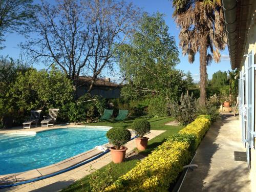 een zwembad in een tuin met potplanten bij La Petite Provence de Touron in Pujols Gironde