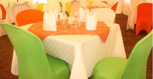 a table with green chairs and a white table cloth at Silent Hill Hotel Kayonza in Kayonza