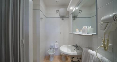 a white bathroom with a sink and a mirror at Mapo Village Plaia in Villanova di Ostuni