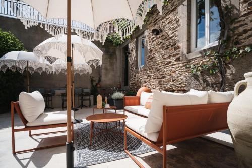 a patio with white chairs and umbrellas at Maison Barthes Suites B&B in Baraqueville