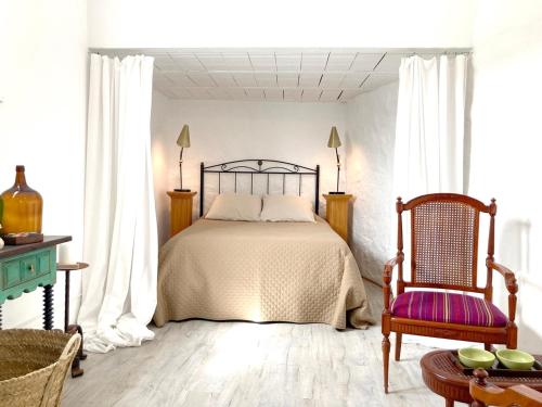 a bedroom with a bed and a chair at Casa Tranquila in Tózar