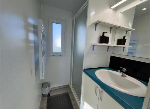 a white bathroom with a sink and a window at Bungalow à la mer in Villeneuve-en-Retz