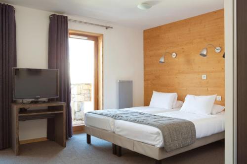 a bedroom with a bed and a flat screen tv at Alpenrose Alpe d'Huez in LʼHuez