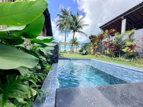 a swimming pool in a yard with palm trees at GREY HOUSE - frente para o mar em Carapibus in Conde