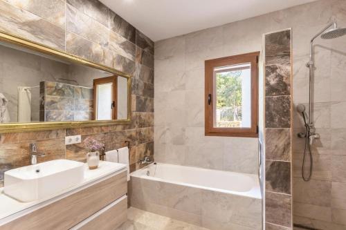 a bathroom with a tub and a sink and a mirror at Villa Maria in Port de Pollensa