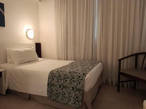 a hotel room with a bed and a chair at Boulevard Plaza in Belo Horizonte
