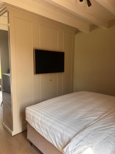 a bedroom with a bed and a flat screen tv on the wall at Maison Cromvoirt in Cromvoirt