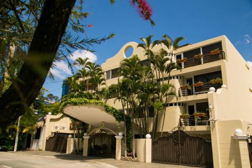 a white building with palm trees in front of it at Apart-Hotel Casa Serena in Guatemala