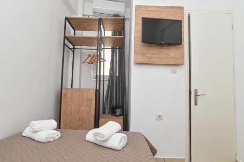 a bedroom with a bed and a tv and towels at Ikaria Therma Blue in Agios Kirykos