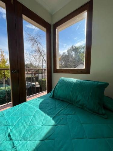 a bedroom with a large green bed with two windows at Global residencial in Rancagua