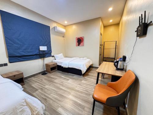 a hotel room with two beds and a table with a chair at Cactus Hotel in Dar es Salaam