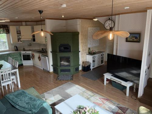 a living room with a green fireplace and a kitchen at Koivuniemen Ranch in Hämeenlinna