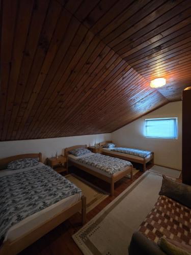 a room with three beds and a wooden ceiling at Horizont apartmans in Jajce