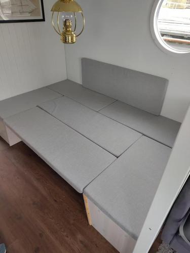 a gray bed in a room with a window at Solvesborg Houseboat with Harbour Views - Sleeps 4 in Sölvesborg