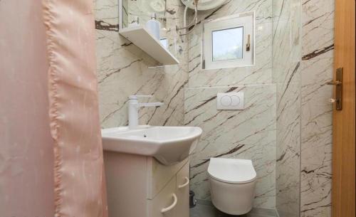 a white bathroom with a sink and a toilet at Miljak in Duće