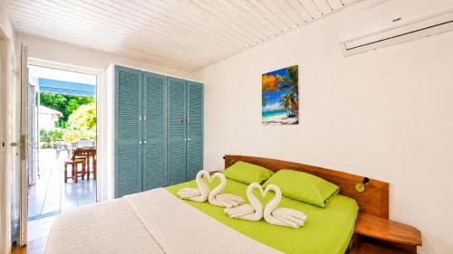 two swans towels on a bed in a bedroom at L'Ecrin d'Oliv - Jardin, Accès plage, Calme assuré in Grand-Bourg