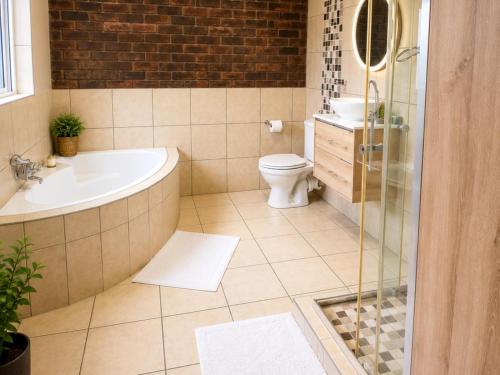 a bathroom with a tub and a toilet and a sink at Comfort e Casa Lodge Near OR Tambo Airport in Kempton Park