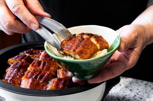 a person holding a bowl of food with a spatula at Richmond Hotel Nagoya Shinkansen-guchi in Nagoya