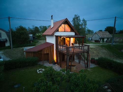 a small house with a large window and a deck at Pajkos Présház in Bakonycsernye