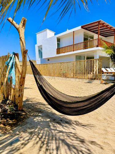 a hammock on the beach in front of a house at El Rubio Beach Bungalows in Zorritos