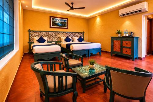 a hotel room with two beds and a table and chairs at Vista Del Lago - Lakeview Homestay in Ambalavayal
