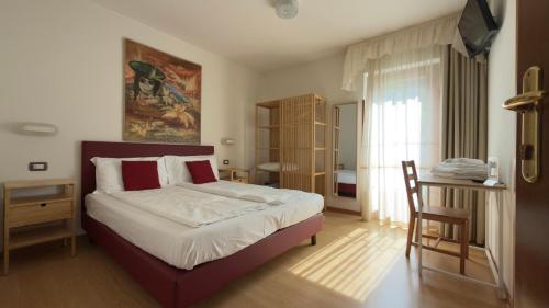a bedroom with a bed and a table and a chair at Casteluce Hotel Funivie in Pinzolo