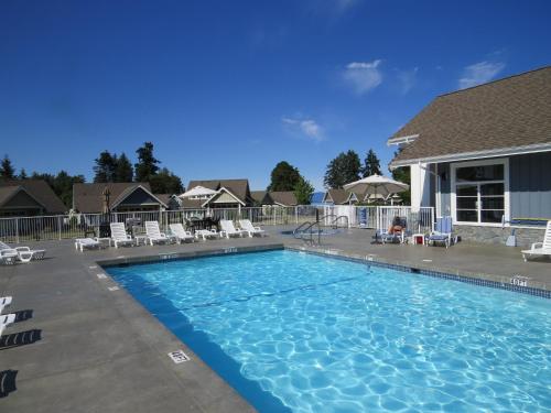 a large swimming pool with chairs and a house at Qualicum Landing Beachside Home in Qualicum Beach