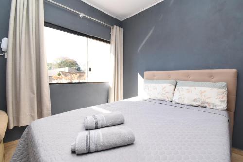 a bedroom with a white bed with a large window at Suite/loft Jardim Botanico in Curitiba