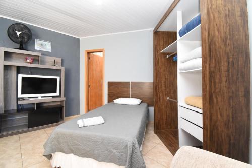 a small bedroom with a bed and a television at Suite/loft Jardim Botanico in Curitiba