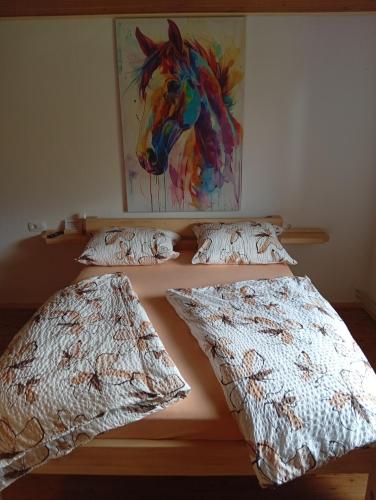 a bed with two pillows and a painting of a horse at Studio pr Vok in Lesce