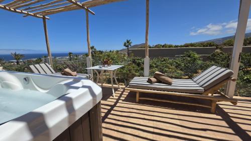 a deck with a tub and two chairs and a table at Apartamentos Finca RiscoTierra in Arafo