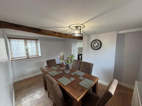 a dining room with a table and chairs and a clock at 3 bed detatched cottage with onsite parking in Rotherham