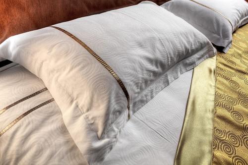 a bed with a white pillow and a gold trim at Voyage Hotel in Almaty