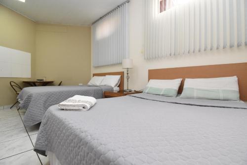 two beds in a hotel room with two beds at Loft Jardim Botânico 2 in Curitiba