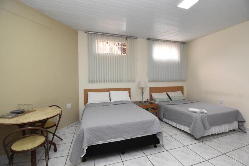two beds in a room with a table and chairs at Loft Jardim Botânico 2 in Curitiba
