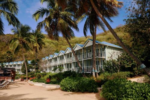 a building on the beach with palm trees at Soho Beach House Canouan in Canouan
