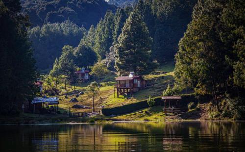 a house on a hill next to a body of water at Hotel El Aguila, Villa del Carbón in Villa del Carbón