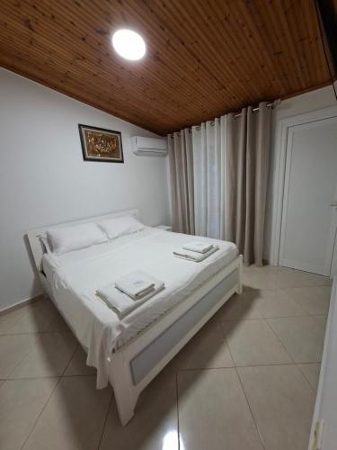 a white bed in a room with a wooden ceiling at Villa Semana Ksamil in Ksamil