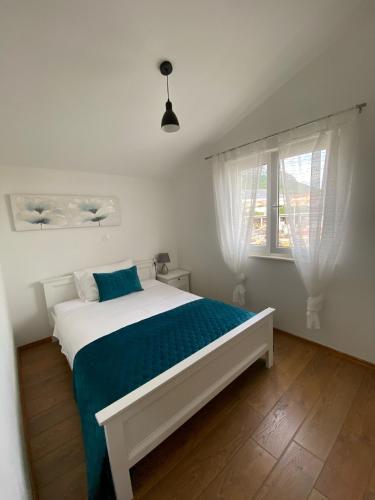 a bedroom with a white bed with a blue blanket at Albatros in Kastel Sucurac