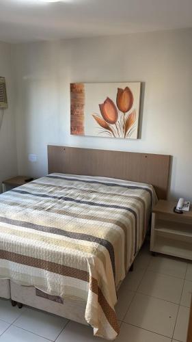 a bed in a bedroom with a painting on the wall at Boulevard Park in Caldas Novas