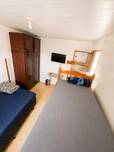 a small room with two beds and a tv at Pensão Meg in São José