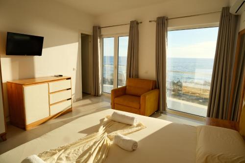 a bedroom with a bed and a chair and a large window at Vila Inheritor in Shëngjin