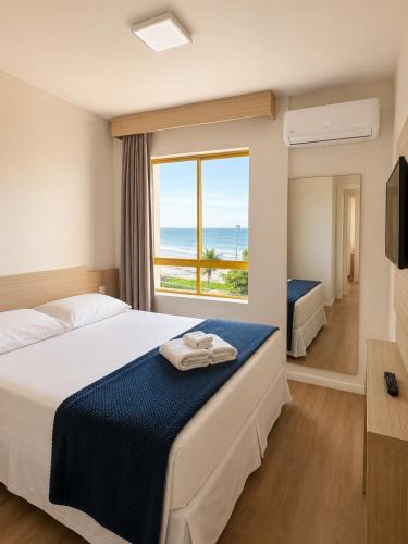 a hotel room with a bed with a view of the ocean at Ingleses Palace Hotel in Florianópolis