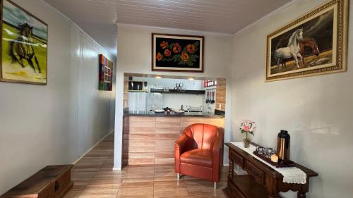 a hallway with a red chair and a kitchen at Haras Cristal Experience in Gama