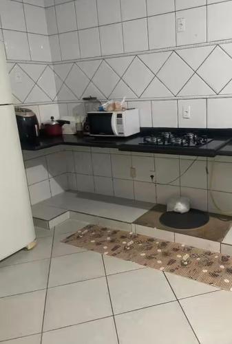 a kitchen with a stove and a microwave at Sua casa longe de casa in Anápolis