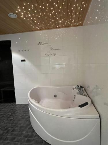 a white tub in a bathroom with lights on the wall at Kurjenpesä in Kalajoki